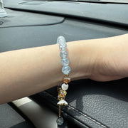 Handmade beaded bracelet with blue crackle beads, white flower charm, and gold crystal accents on hand